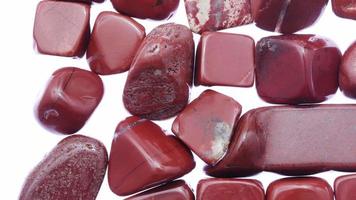 Red jasper heap jewel stones texture on white light background. Moving right seamless loop backdrop. video