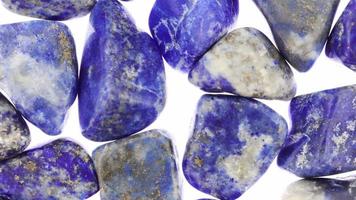 Lapis lazuli heap jewel stones texture on white light background. Moving right seamless loop backdrop. video