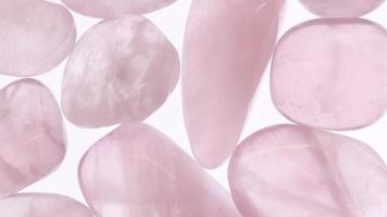 textura de montón de joyas de cuarzo rosa sobre superficie clara. fondo de guijarros minerales. moviendo el fondo de bucle sin costuras a la derecha. video