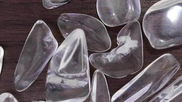 Clear quartz jewel heap on varnished brown wood background. Moving right seamless loop backdrop. video