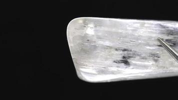 chiaro kunzite gioiello pietra struttura nel pinzetta su nero sfondo. macro avvicinamento. in movimento giusto senza soluzione di continuità ciclo continuo sfondo. video