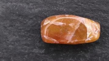 Red silk jade jewel stone texture on black stone background. Macro closeup. Moving right seamless loop backdrop. video