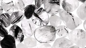 Tourmalinated quartz heap jewel stones texture on white light background. Moving right seamless loop backdrop. video