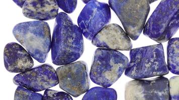 Lapis lazuli heap jewel stones texture on white light background. Moving right seamless loop backdrop. video