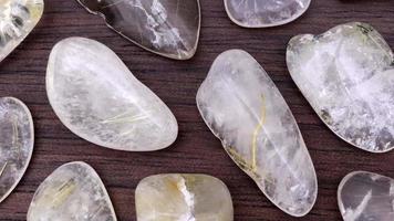 Rutilated quartz rare jewel stones texture on brown varnished wood background. Moving right seamless loop backdrop. video