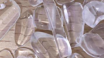 Clear quartz jewel heap on varnished light wood background. Moving right seamless loop backdrop. video