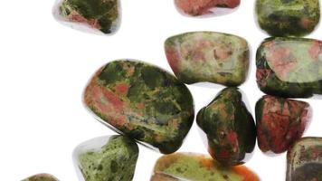 Unakite heap up jewel stones texture on white light isolated background. Moving right seamless loop backdrop. video