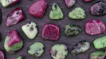 Ruby zoisite rare jewel stones texture on black stone background. Moving right seamless loop backdrop. video