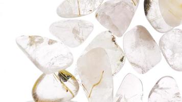 Rutilated quartz heap up jewel stones texture on white light isolated background. Moving right seamless loop backdrop. video