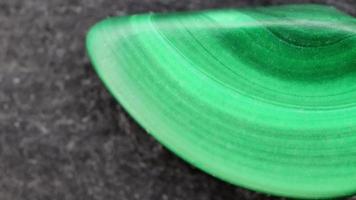 Malachite jewel stone texture on black stone background. Macro closeup. Moving right seamless loop backdrop. video