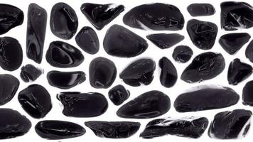 Black tourmaline rare jewels set texture on isolated white background. Moving right seamless loop backdrop. video