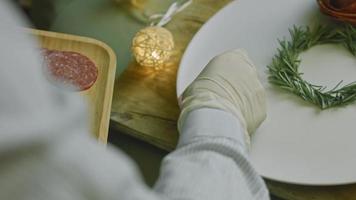 plato de charcutería con salami, diferentes tipos de queso. tiene frutos secos, frutos secos varios y miel. arreglo de vacaciones con velas encendidas video