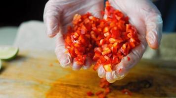 ik houden een zoet rood kapia paprika's besnoeiing in klein stukken. macro het schieten video