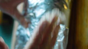 The chef arranges the aluminum foil in a very large burrito video