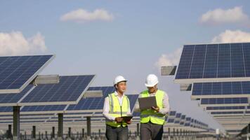 Two Asian Technician and Engineer man use laptop computer while check efficiency of sun for examination on solar panel construction video