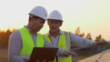 Two Asian Technician and Engineer man use laptop computer while check efficiency of sun for examination on solar panel construction video