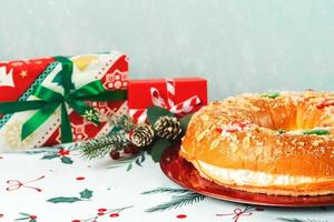 roscon de reyes con crema y adornos navideños en un plato rojo. concepto del día de reyes pastel de reyes magos postre típico español para navidad