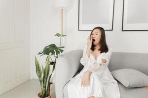 Thai woman yawning on the sofa in the living room photo