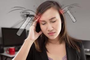 Una mujer asiática agotada y estresada que tiene un fuerte dolor de cabeza por tensión en la oficina. foto