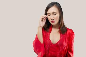 Asian women in a red silk nightgown have rubbing in the eye. Have itching in the eye. photo