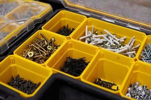 Yellow storage case with screws, nuts, bolts, nails and other small tools for handyman, close up photo