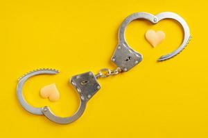 Opened handcuffs on yellow background. photo