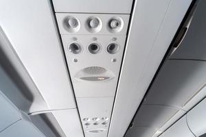 Airplane air conditioning control panel over seats. Stuffy air in aircraft cabin with people. New low-cost airline. photo