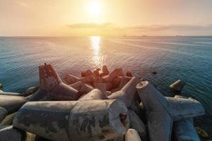 Beautiful sunset seascape. Breakwaters tetrapods ashore of pier. Cargo ships on the horizon. Travel dreams and motivation photo