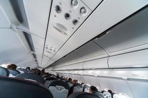 panel de control del aire acondicionado del avión sobre los asientos. aire viciado en la cabina del avión con gente. nueva aerolínea de bajo costo foto