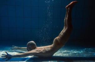 hombre de deporte atlético bajo el agua en la piscina. deportes, yoga, concepto de buceo libre