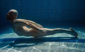 hombre de deporte atlético bajo el agua en la piscina. deportes, yoga, concepto de buceo libre foto