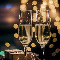 champagne glasses against holiday lights and new year fireworks photo