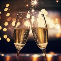 champagne glasses against holiday lights and new year fireworks photo