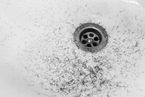 Dirty wash hand basin showing grungy drain with bits of hair photo