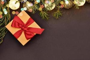 Gift with garland in the form of wicker balls on a dark background with a sprig of spruce and bokeh lights. photo