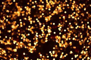 círculos de oro bokeh sobre un fondo negro. luces de colores de navidad. cubrir foto