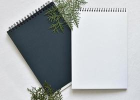 mockup from a two black and white sketchbook on a spring lying on a linen tablecloth with sprigs of green thuja photo