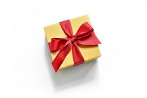 box with a red ribbon on a white background with a shadow. presentation of the gift. present in beige packaging photo