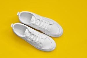 white sneakers isolated on a yellow background. Element for design. Sport shoes. photo