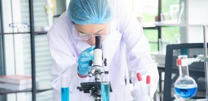 Asian woman scientist, researcher, technician, or student conducted research or experiment by using microscope which is scientific equipment in medical, chemistry or  biology laboratory photo