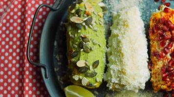 messicano Mais elote nel tre modi. premuto con formaggio, guacamole e Melograno. maxican bandiera video