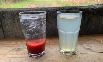 a glass of strawberry soda and lemon soda served on a wooden table photo