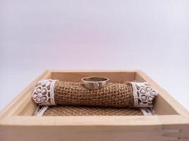 wedding ring placed on a wooden ringbox with a burlap cloth as a base. With white isolated background photo