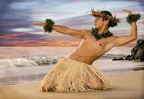 guapo bailarín de hula masculino en la playa al atardecer con falda de hierba de traje tradicional. foto