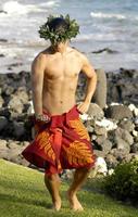 Male hula dancer performs at the shoreline with manly moves and traditional male hula poses. photo
