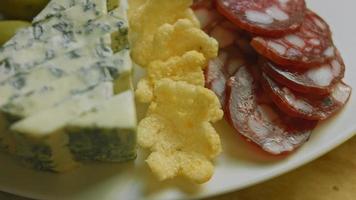 charcuterie plate au salami, différentes sortes de fromages. il contient des fruits secs, diverses noix et du miel. arrangement de vacances avec des bougies allumées video