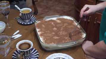 la mano de una mujer divide el pastel recién cocinado en pedazos. ella presenta un postre dulce con té. video