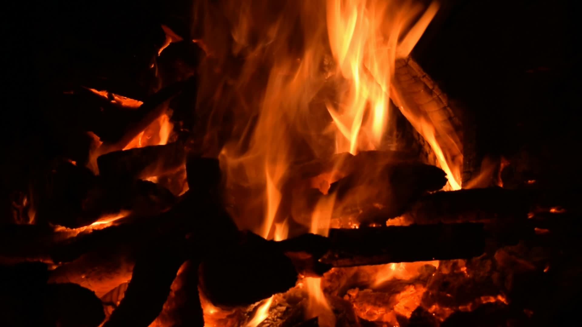 Une flamme orange vif de feu brûle sur un fond sombre. Bois de