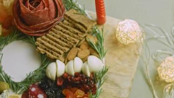 assiette de charcuterie avec salami, différentes sortes de fromages. il contient des fruits secs, diverses noix et du miel. arrangement de vacances avec des bougies allumées video