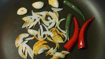 el chef está friendo verduras. cebollas y pimientos rojos y verdes marrones video